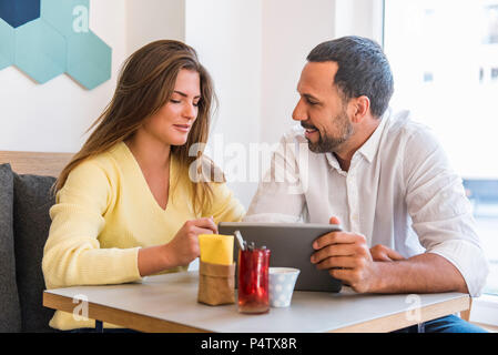 Jeune femme et l'homme partager comprimé dans un cafe Banque D'Images