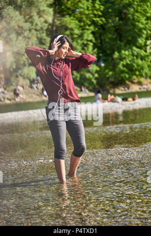 Jeune femme à l'écoute de la musique avec un casque et un téléphone cellulaire à danser à Riverside Banque D'Images