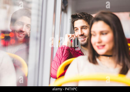 UK, Londres, portrait de jeune homme au téléphone dans un bus Banque D'Images