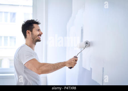 Smiling man painting wall dans l'appartement Banque D'Images