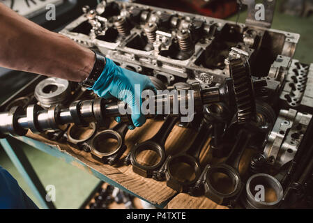 Close-up of mechanic holding le vilebrequin du moteur d'une voiture à un atelier Banque D'Images