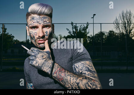 Portrait de jeunes tatoués man smoking a cigarette Banque D'Images