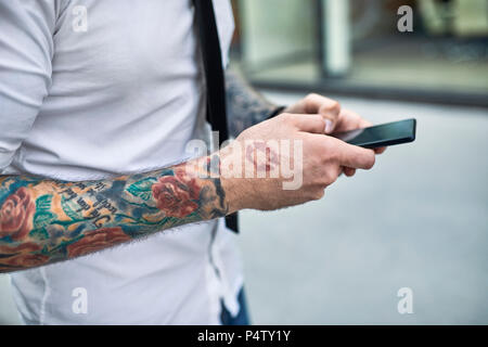 Jeune homme tatoué avec à l'aide de téléphone intelligent Banque D'Images