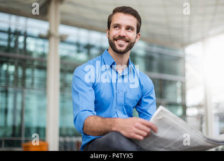 Smiling young woman outdoors with newspaper Banque D'Images