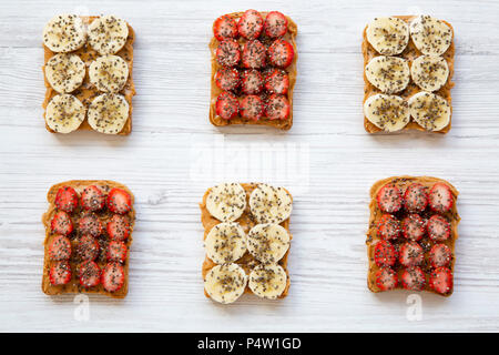 Petit déjeuner sain. Toasts vegan avec du beurre d'arachides, fruits et graines de chia blanches sur fond de bois, vue du dessus. Banque D'Images