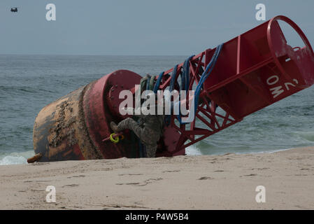 Le Sgt. 1re classe Chris Richards de la Connecticut National Guard se prépare à grimper au sommet d'une 12 000 livres de bouées échouées, le mardi 9 mai 2017, près de Chatham, Massachusetts. Il a joint les élingues de levage à un hélicoptère CH-47 Chinook qui a levé la bouée de la plage. Banque D'Images