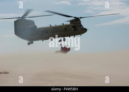 Le Sgt. 1re classe Chris Richards de la Connecticut National Guard attache un 12 000 livres à la bouée échouée sur un hélicoptère CH-47 Chinook, le mardi 9 mai 2017, près de Chatham, Massachusetts. Le Chinook a levé la bouée de la plage et a apporté à l'étranger où le Chêne garde-côte l'a pris. Banque D'Images