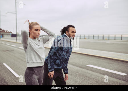 Jeune couple divers dans les vêtements de sport l'échauffement et se concentre avant une course ensemble sur l'image Banque D'Images