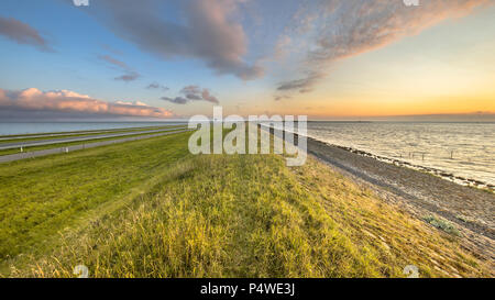 Afsluitdijk dutch endiguer à l'autoroute et piste le paysage pendant le coucher du soleil avec ciel assombri Banque D'Images