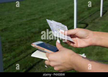 Close up de filles mains tenant le pari et le programme des courses avec téléphone à Royal Ascot Racecourse Banque D'Images