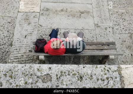 Couple de personnes âgées assis assis ensemble en attente sur banc en bois bénéficiant d'une pause, England, UK Banque D'Images