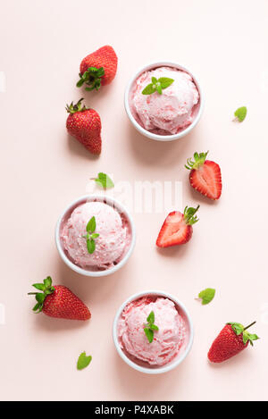 La crème glacée aux fraises et de fraises fraîches sur fond rose, vue du dessus. Trois boules de glace à la fraise, dessert d'été en bonne santé. Banque D'Images