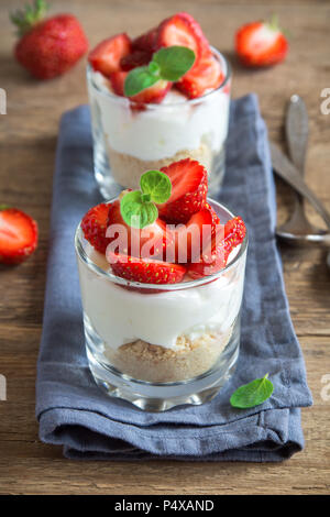 Bagatelle aux fraises dessert mini dans les verres avec des fraises fraîches et fromage à la crème sur fond de bois. Maison saine potrion dessert. Banque D'Images