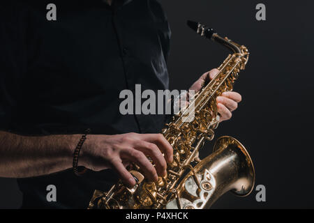 Cropped shot of man playing saxophone sur noir Banque D'Images