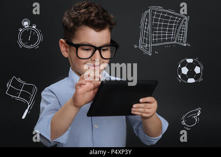 Boy holding a tablet positive et regarder le football en ligne Banque D'Images