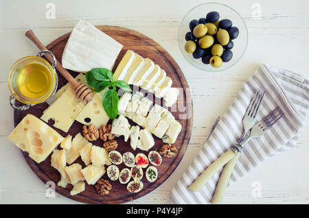 Assiette de fromage : Parmesan, cheddar, gouda, gorgonzola, brie et d'autres avec des noix, des olives et du miel sur planche de bois sur fond blanc. Appetiz savoureux Banque D'Images