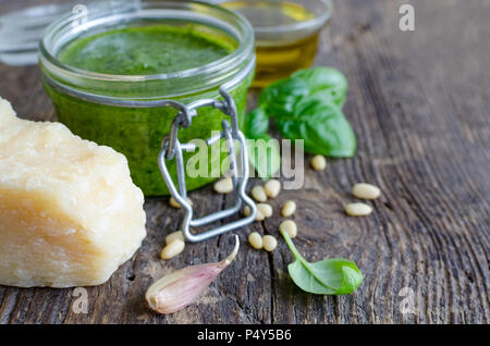 Le pesto genovese - sauce au basilic vert italien traditionnel avec de l'huile d'olive, les feuilles de basilic, le Parmesan, l'ail et les pignons de pin sur le vieux fond de bois. Banque D'Images