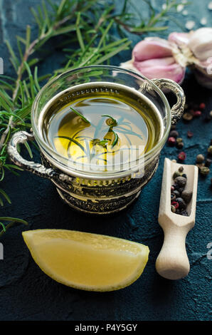 L'huile d'olive aux épices - romarin, l'ail, le citron, le sel et le poivre sur la table en pierre sombre. Ingrédients de cuisine concept. L'alimentation saine. Banque D'Images