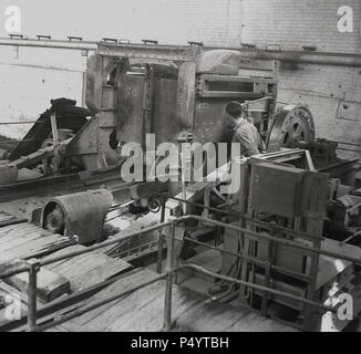 dans les années 1950, un homme travaillant à une machine, perphse un moulin de la matière première, de la mudstone ou de la roche. Les bricksworks de la London Brick Company en Angleterre d'après-guerre, sont devenus les plus grands brickworks au monde reliant 8 villages à travers la vallée de Marston, y compris le célèbre « village de motels » de Stegartby, Qui fournissait des logements, des installations sportives et sociales à la main-d'œuvre, ainsi qu'une église, une école, un magasin et un GP. Banque D'Images