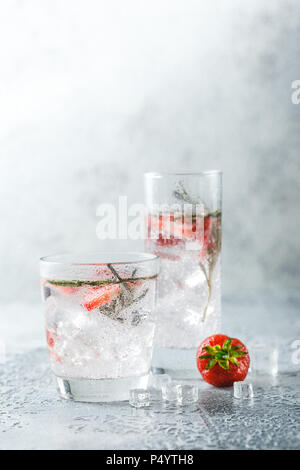 Boissons ou cocktails sans alcool avec des fraises et du romarin et de la glace dans le verre de lunettes. Espace libre pour le texte. Banque D'Images