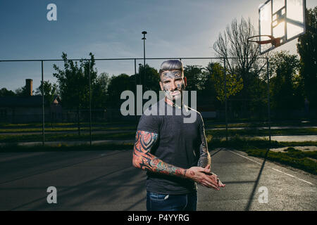 Portrait de jeune homme tatoué sur le terrain de basket-ball Banque D'Images