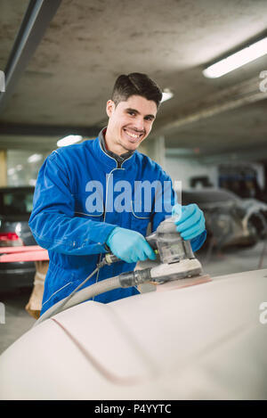 Portrait of smiling man polir le capot d'une voiture à un atelier Banque D'Images