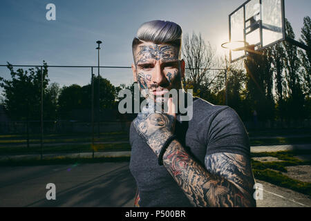 Portrait de jeune homme tatoué sur le terrain de basket-ball Banque D'Images
