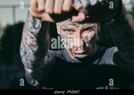 Portrait de jeune homme tatoué à l'extérieur de serrer les poings Banque D'Images