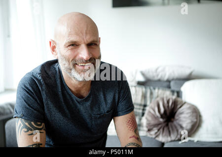 Tattooed man at home sitting on couch Banque D'Images