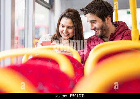 UK, Londres, happy young couple in bus looking at cell phone Banque D'Images