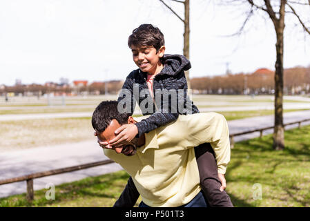 Happy father carrying son piggyback dans un parc Banque D'Images