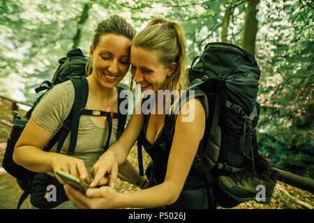 Deux jeunes femmes heureux en randonnée using cell phone Banque D'Images