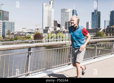 Smiling mature man with headphones tournant sur le pont dans la ville Banque D'Images