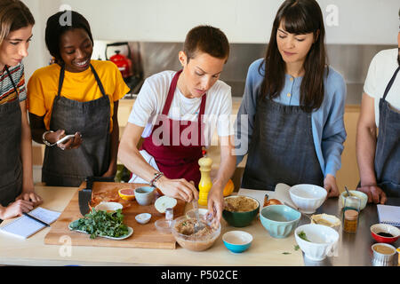 Les amis et l'instructeur dans un atelier de cuisine la préparation des aliments Banque D'Images