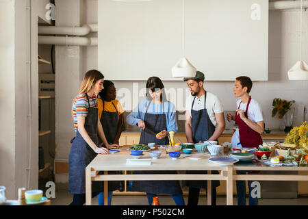 Les amis et l'instructeur dans un atelier de cuisine la préparation des aliments Banque D'Images