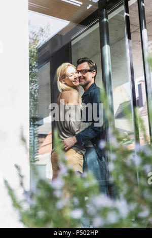 Couple debout sur la terrasse de leur maison Banque D'Images