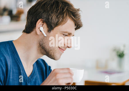 L'homme souriant dans un café avec écouteurs de boire du café Banque D'Images