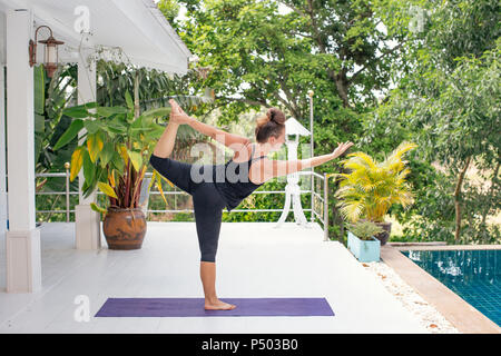 Woman practicing yoga on terrasse au bord de l'eau Banque D'Images