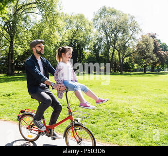 Heureux père équitation location avec fille assis au guidon dans un parc Banque D'Images