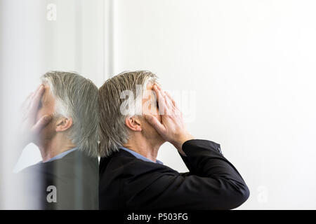 Desperate businessman leaning on window Banque D'Images