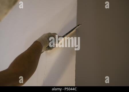 L'application putty travailleur sur le mur avec une spatule, l'accent peu profondes Banque D'Images