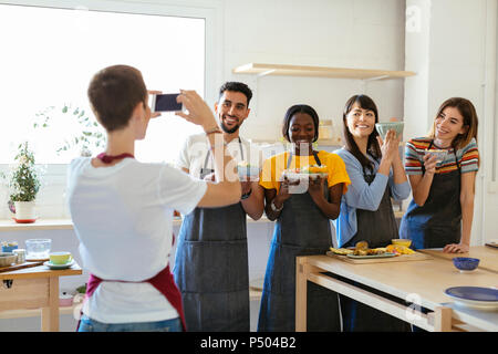 Formateur de prendre une photo d'amis dans un atelier de cuisine Banque D'Images