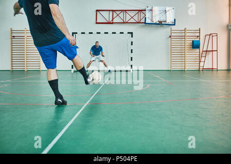 Deux hommes jouer tir au but de soccer intérieur Banque D'Images