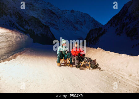 Couple Sledding in snow-covered landscape at night Banque D'Images