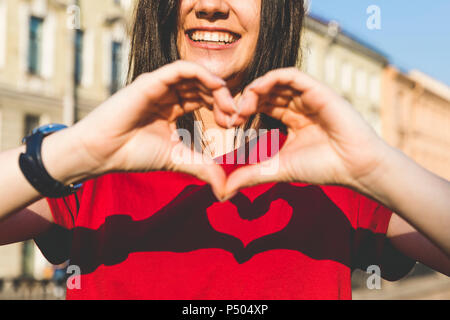 Woman's hands shaping cœur, l'ombre rouge sur t-shirt Banque D'Images