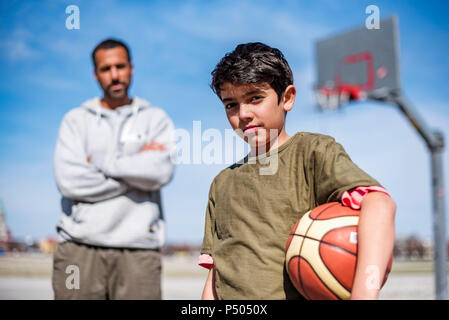 Portrait de jeune garçon posant avec le père de basket-ball extérieur Banque D'Images