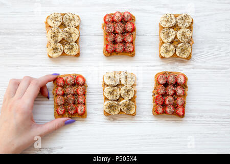 Jeune fille prend vegan pain perdu aux fruits, graines, beurre d'arachide over white background, vue du dessus. Concept de suivre un régime. À partir de ci-dessus. Banque D'Images