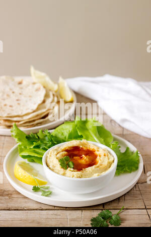 L'hoummos avec de l'huile d'olive et de paprika, servi avec pain pita, citron et de feuilles de laitue. Focus sélectif. Banque D'Images