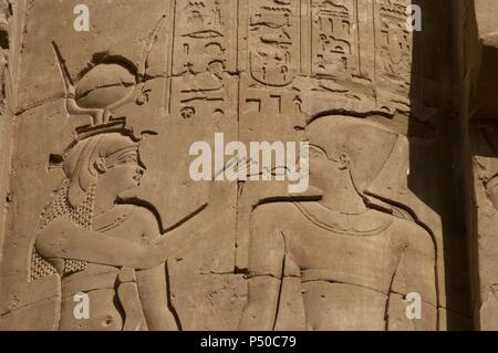 L'Égypte. Edfou. Temple d'Horus. Relief représentant une divinité égyptienne de donner la clé de la vie, l'ankh, le Pharaon. Banque D'Images