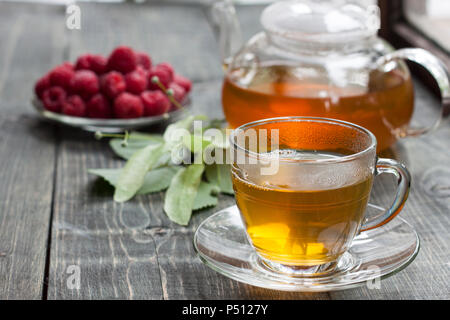 La framboise et le thé vert de un linden sur une table en bois Banque D'Images